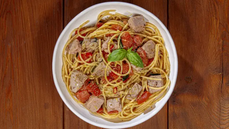 Spaghetti al tonno, un classico profumato, come la spaghetti al tonno ricetta della nonna, con pomodorini e basilico fresco.